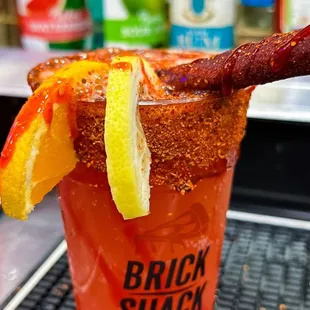 a bloody drink with bacon and orange slices