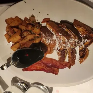 Brioche French Toast with a side of bacon and potatoes .
