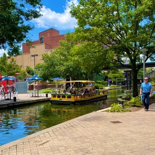 A Bricktown Water Taxi cruises past Brickopolis mini golf on a beautiful day in July, 2021