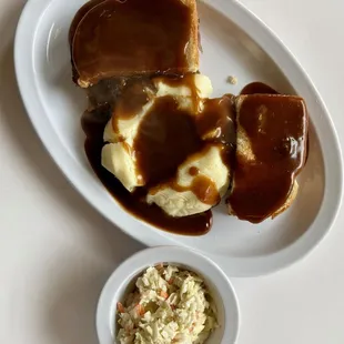 Roast beef dinner with mashed potatoes, gravy and coleslaw.