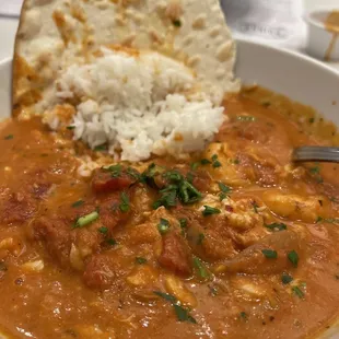 a bowl of seafood stew with rice and bread