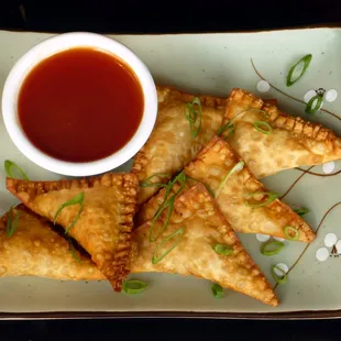 a plate of fried pastries and a bowl of sauce