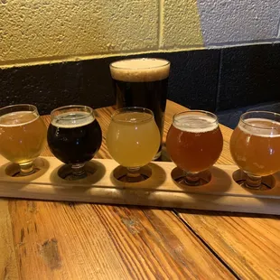 a flight of beers on a wooden tray