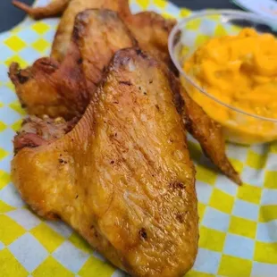 a plate of chicken wings and a bowl of sauce