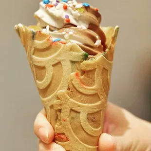 a person holding an ice cream cone with sprinkles