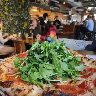 Make your own pizza. A tower of arugula, vegan cheese, chorizo and peppers