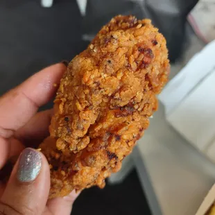 a hand holding a piece of fried chicken