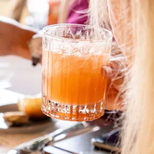 a woman holding a glass of orange juice