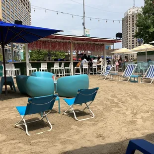 a woman sitting in a blue chair on the beach