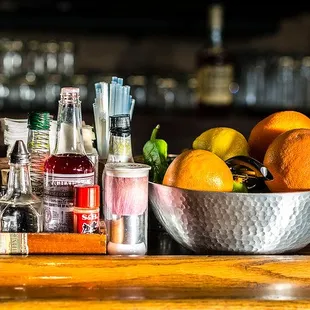 a bowl of oranges and liquor on a bar counter