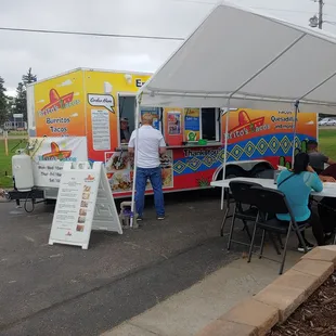 a group of people sitting at a table in front of a food truck