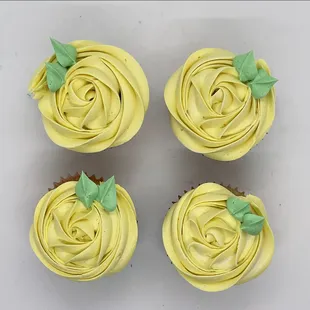four cupcakes with yellow frosting