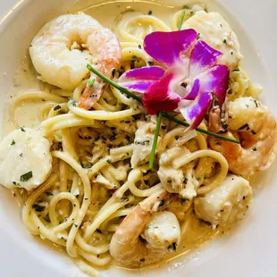 a plate of pasta with shrimp and scallops