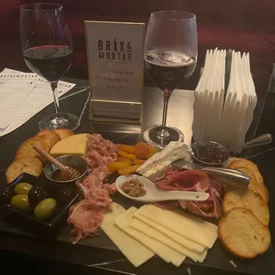 a platter of meat, cheese, olives, and bread
