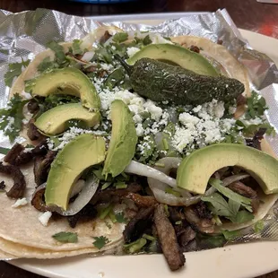 Mini beef tacos with avocado, grilled onions and jalapeño, cilantro and cotija cheese. Delicious.
