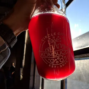 a person holding a glass of red liquid