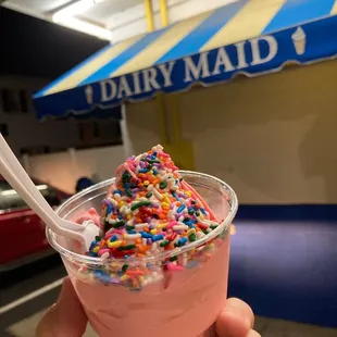 a hand holding a cup of ice cream with sprinkles