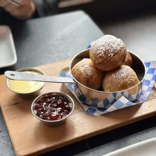 a bowl of powdered sugared donuts and a bowl of jam