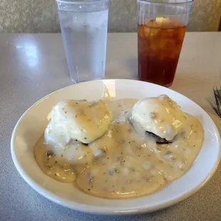 Sausage Benedict - Buttermilk Biscuit topped with sausage patty, cheddar cheese, poached eggs, and smothered with sausage gravy