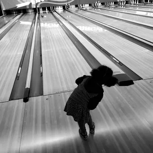 a woman bending over to pick up a bowling ball