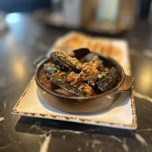 Mussels: Chilean Blue Mussels Sauteed in a Gajun Garlic Sauce Topped w/ House-made Pork Belly. Baked Crostini's | $12.99