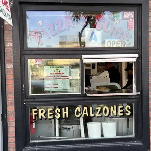 a window with a sign that says fresh calzones