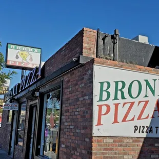 a brick building with a sign for bronx pizza