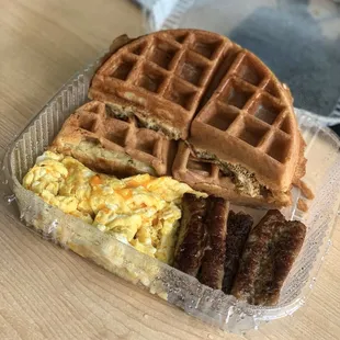 Waffle, scrabbled egg with cheese, and pork sausage.