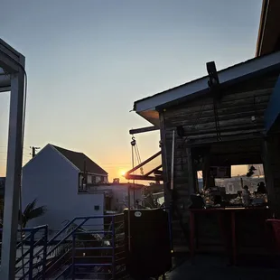 the sun setting over the rooftop of a restaurant