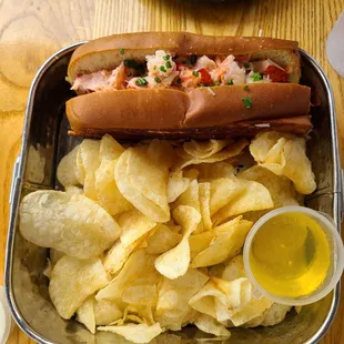 a hot dog and chips in a lunch tin