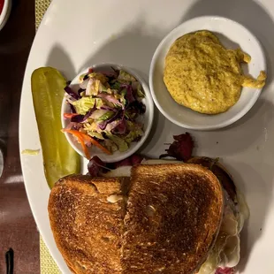a grilled cheese sandwich with coleslaw and pickles