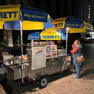 a woman standing in front of a food cart