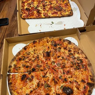 two pizzas in boxes on a table