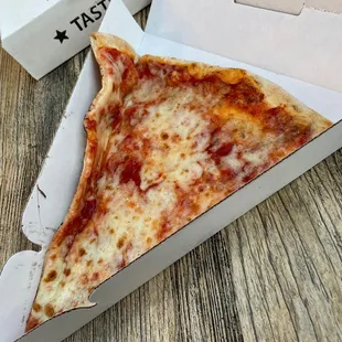 a slice of cheese pizza in a box