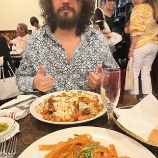 a man sitting at a table with a plate of pasta