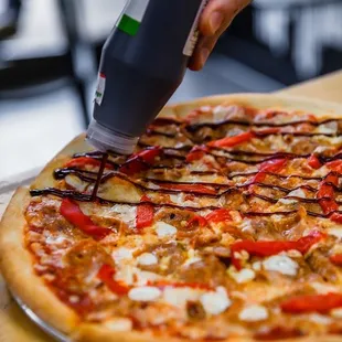 a person putting toppings on a pizza