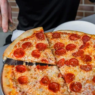 a man cutting a pepperoni pizza