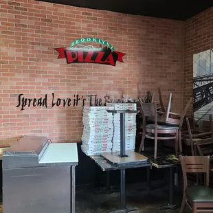 pizza boxes stacked on a table in front of a brick wall