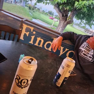 a man sitting at a table with two cans of beer
