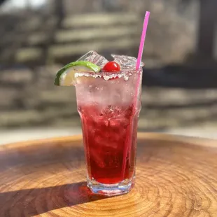 a cocktail with a cherry and lime garnish