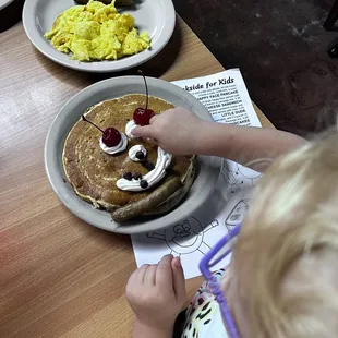 a child eating pancakes and eggs