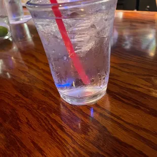a glass of water with a red straw