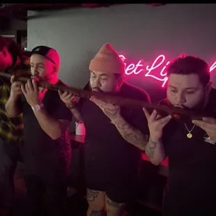 a group of men standing in front of a neon sign