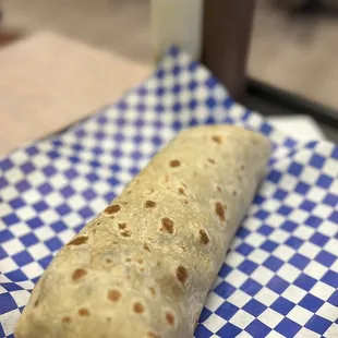 a burrito on a blue and white checkered napkin