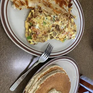 Meat, tomatoes and green peppers omelette home fries and short stack of pancakes.