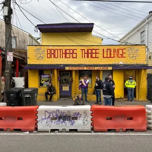 a group of people standing in front of a yellow building