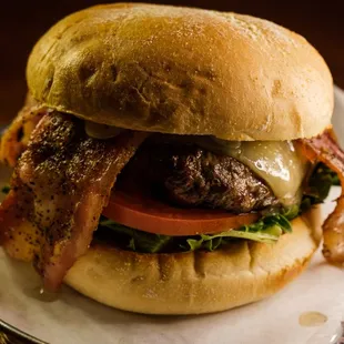a burger with bacon, tomato, and lettuce