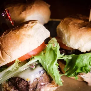 two burgers with lettuce and tomato