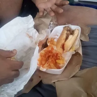 two hands reaching for a hot dog