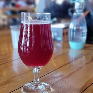 a glass of red wine on a wooden table